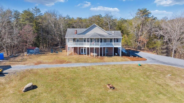 view of front of home featuring stairs, aphalt driveway, a view of trees, and a front yard