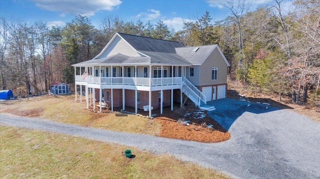 view of front of property featuring a storage unit, a porch, an attached garage, driveway, and stairs