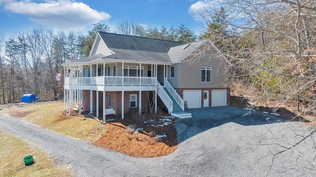 view of front of home with aphalt driveway, an attached garage, stairs, a porch, and brick siding