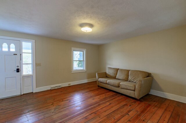 living room with hardwood / wood-style flooring, baseboards, visible vents, and a textured ceiling