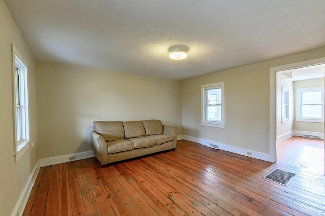 unfurnished living room featuring baseboards, visible vents, and hardwood / wood-style floors