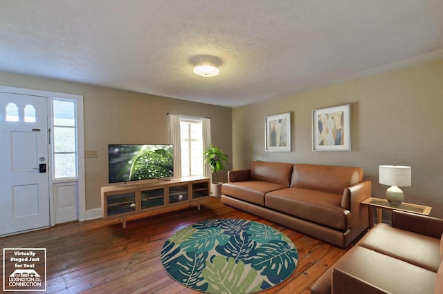 living area with hardwood / wood-style flooring, baseboards, and a textured ceiling