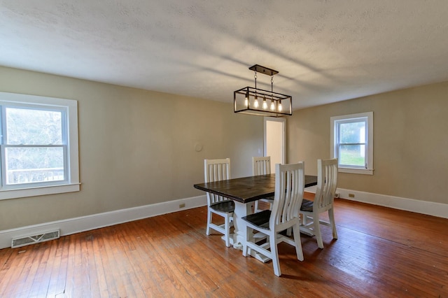 dining room with a textured ceiling, dark wood finished floors, visible vents, and baseboards