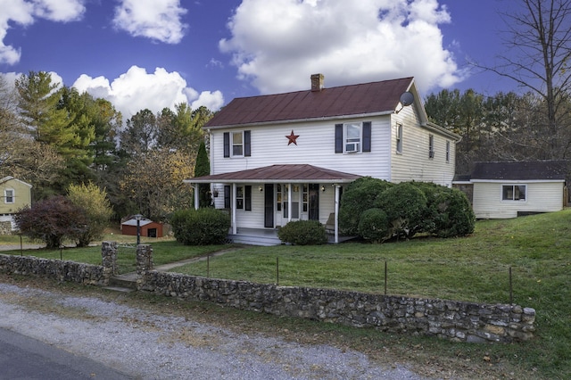 view of front of house featuring metal roof, covered porch, an outdoor structure, a chimney, and a front yard