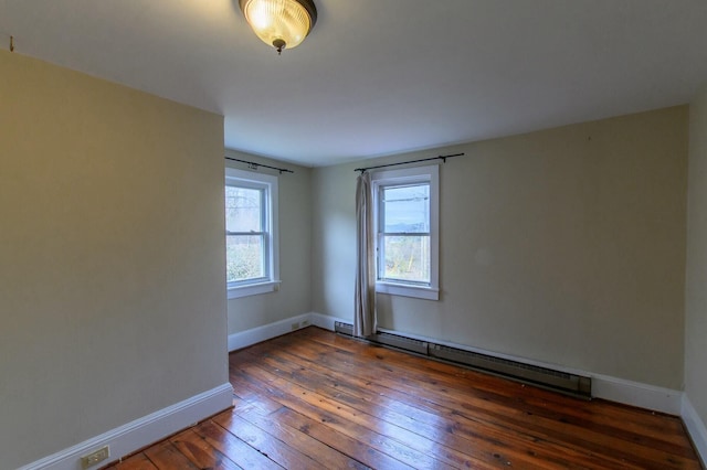 spare room featuring baseboard heating, hardwood / wood-style flooring, and baseboards