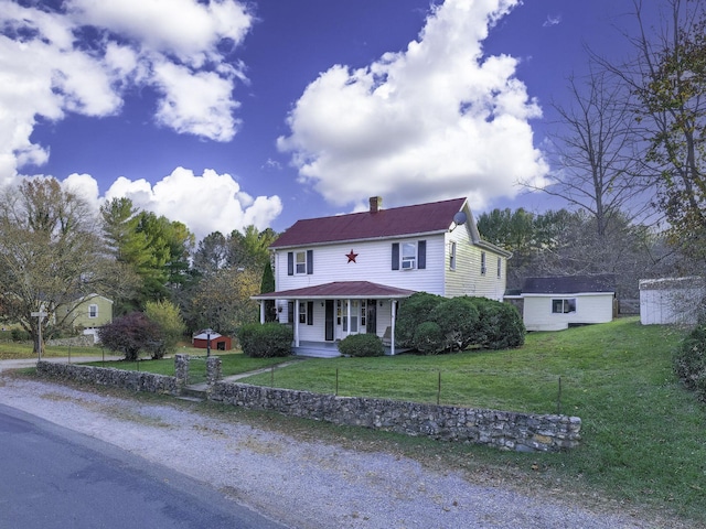 view of front of home with covered porch, a chimney, a front lawn, and an outdoor structure