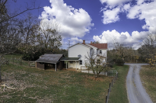 view of side of property with a chimney, fence, a deck, and a lawn