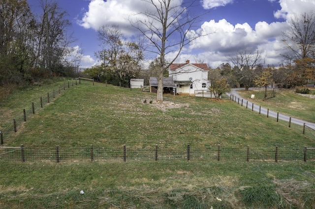 view of yard with fence and a rural view