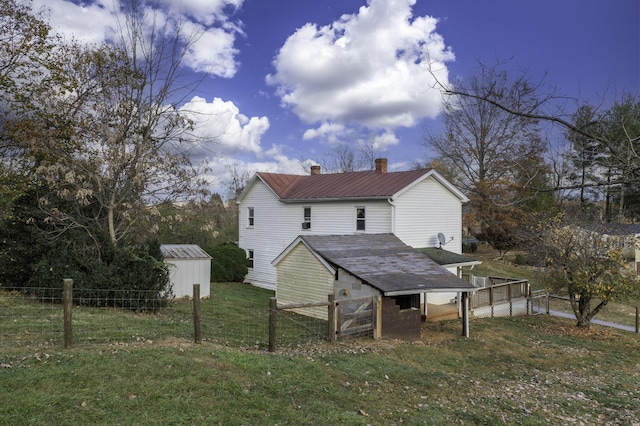 rear view of house with metal roof, an outdoor structure, fence, a yard, and a shed