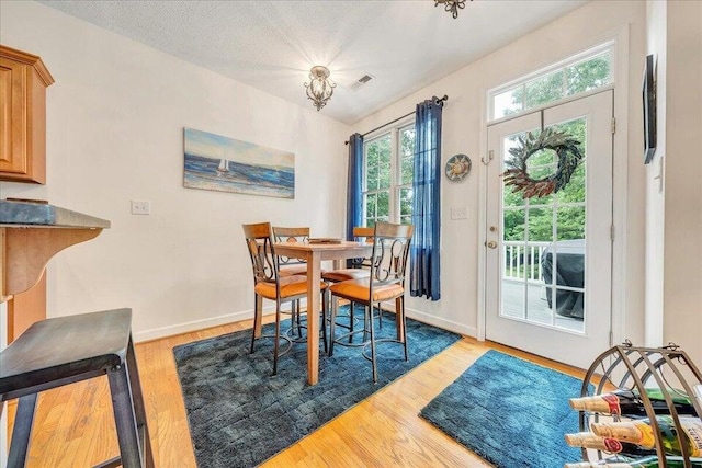 dining area with visible vents, a textured ceiling, baseboards, and wood finished floors