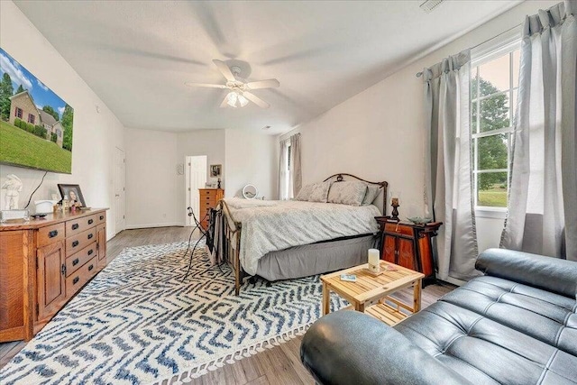 bedroom with ceiling fan, multiple windows, baseboards, and light wood-style floors