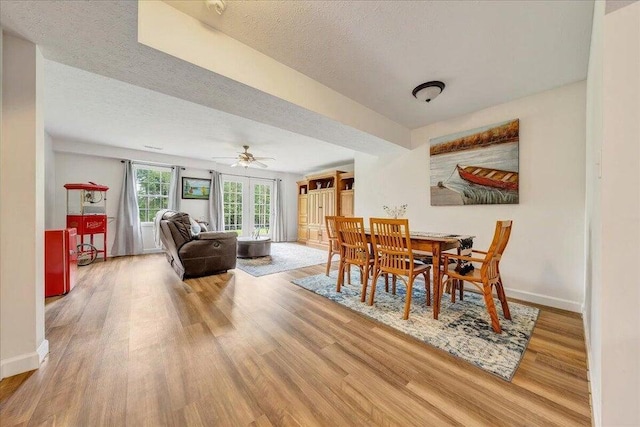 dining area with a textured ceiling, baseboards, and wood finished floors