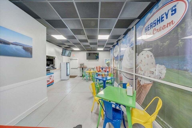 recreation room with concrete flooring and a drop ceiling