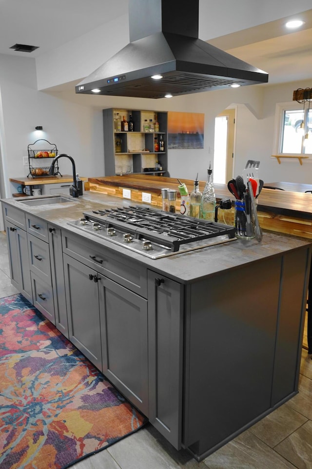 kitchen featuring stainless steel gas cooktop, a sink, island exhaust hood, and gray cabinetry