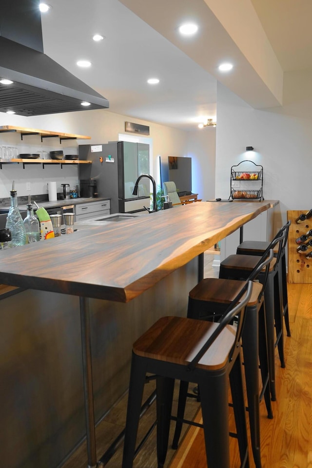 kitchen featuring a kitchen bar, wooden counters, light wood finished floors, and island exhaust hood