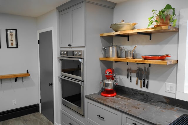 kitchen with open shelves, double oven, gray cabinets, and baseboards