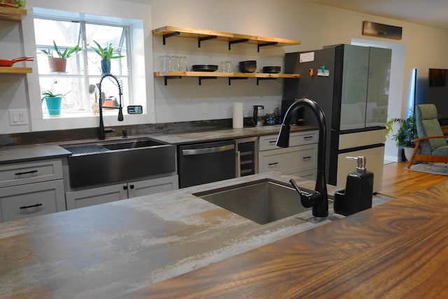 kitchen with freestanding refrigerator, dishwasher, a sink, and open shelves