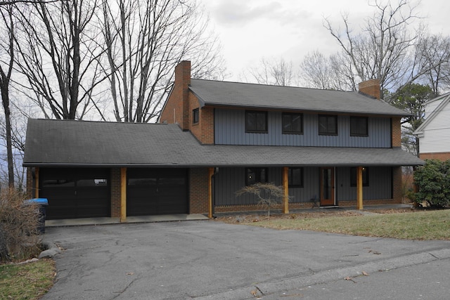 view of front of house with aphalt driveway, a chimney, a porch, an attached garage, and board and batten siding