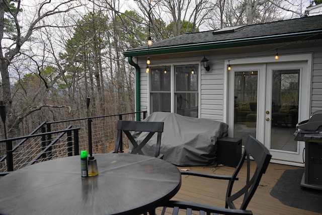 wooden terrace with outdoor dining area, grilling area, and french doors