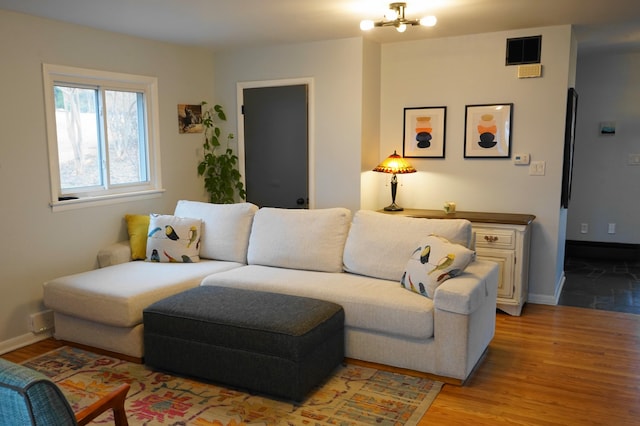 living room featuring visible vents, a notable chandelier, light wood-style flooring, and baseboards