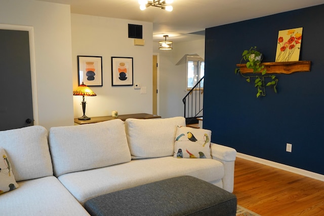 living area with stairs, wood finished floors, visible vents, and baseboards