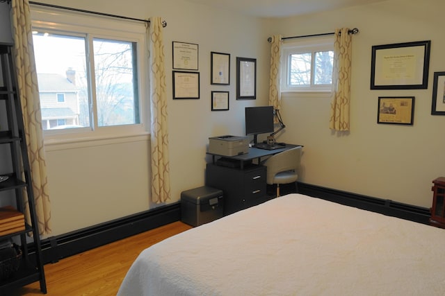 bedroom featuring a baseboard radiator, baseboards, and wood finished floors