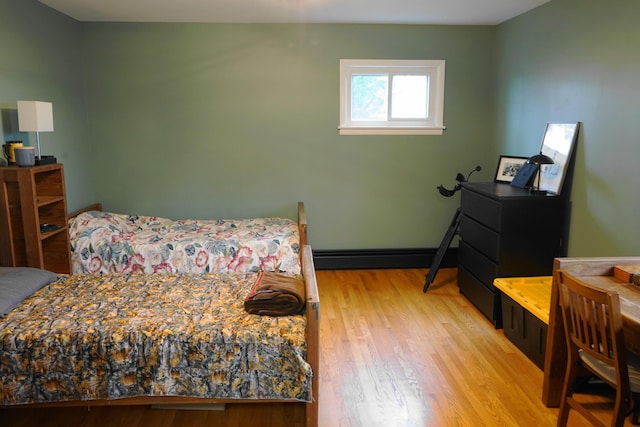 bedroom with baseboards, baseboard heating, and wood finished floors