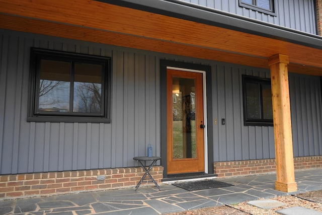 view of exterior entry featuring covered porch and board and batten siding