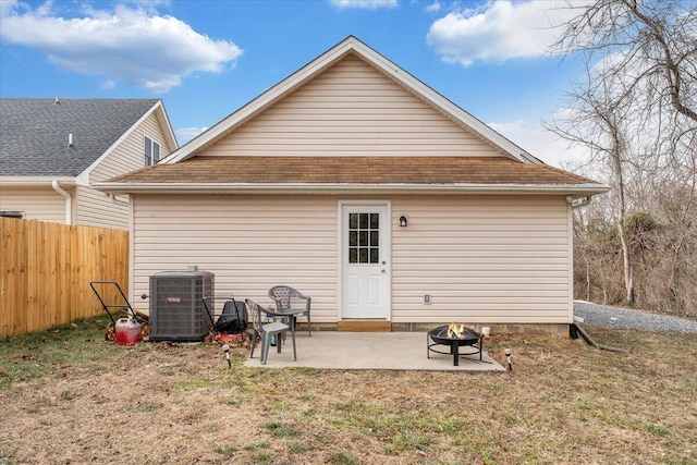 rear view of property featuring a patio, cooling unit, a fire pit, fence, and a yard