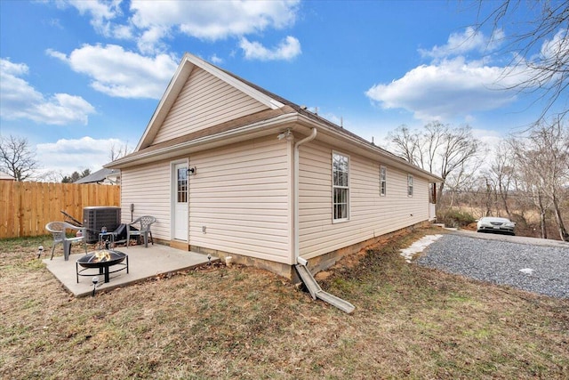 view of side of property with central AC, fence, a fire pit, and a patio