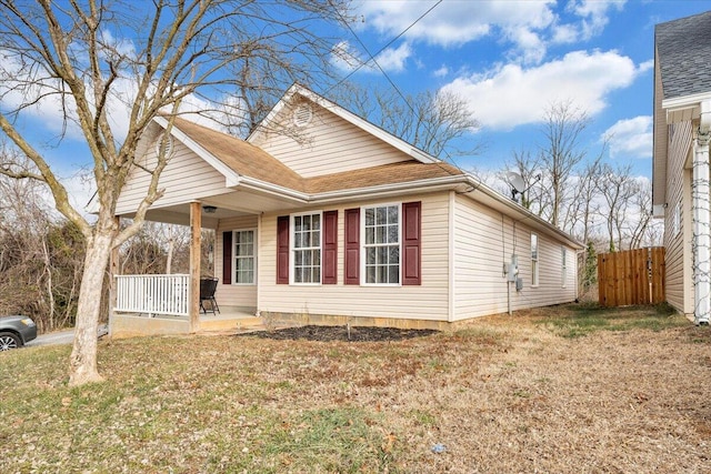 view of front of property featuring covered porch, a front yard, and fence