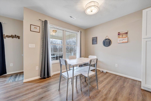 dining room featuring light wood-style floors, baseboards, and visible vents