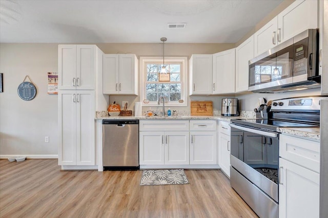 kitchen with a sink, visible vents, white cabinetry, appliances with stainless steel finishes, and light wood finished floors