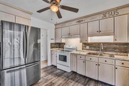 kitchen featuring light countertops, freestanding refrigerator, white electric range, and backsplash