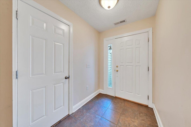 foyer featuring visible vents, baseboards, and a textured ceiling