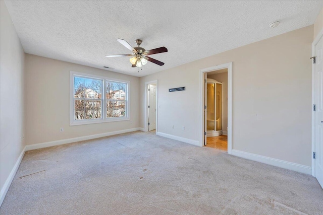 empty room with baseboards, light colored carpet, ceiling fan, and a textured ceiling