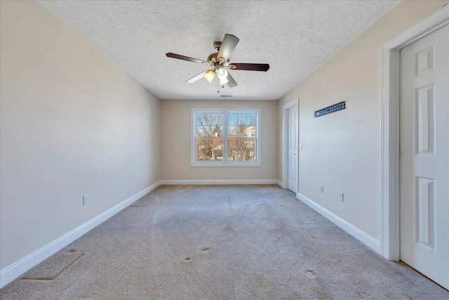 empty room featuring ceiling fan, a textured ceiling, baseboards, and carpet floors