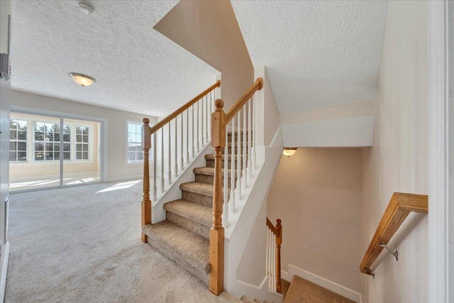 stairs with a textured ceiling, baseboards, and carpet floors