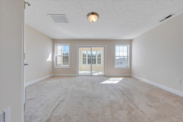 unfurnished room with carpet, visible vents, and baseboards