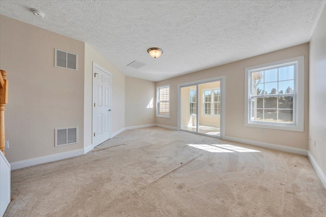 carpeted empty room featuring visible vents, baseboards, and a textured ceiling