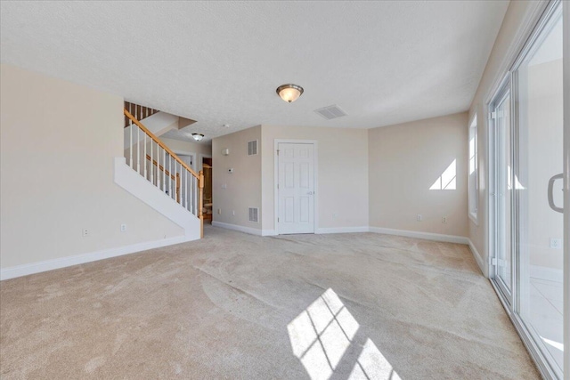 unfurnished room featuring stairway, visible vents, baseboards, and light carpet