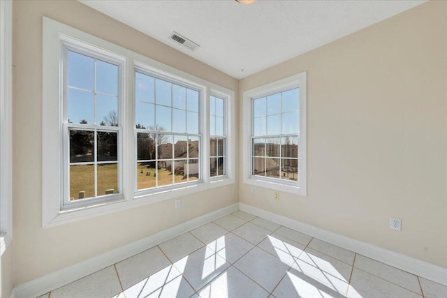 tiled spare room featuring visible vents and baseboards