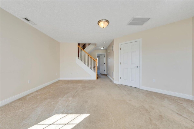 spare room with stairs, baseboards, visible vents, and a textured ceiling