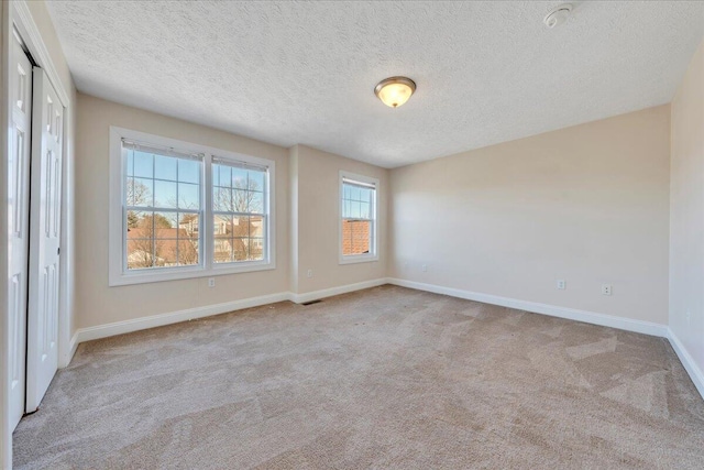 spare room featuring visible vents, a textured ceiling, baseboards, and carpet floors