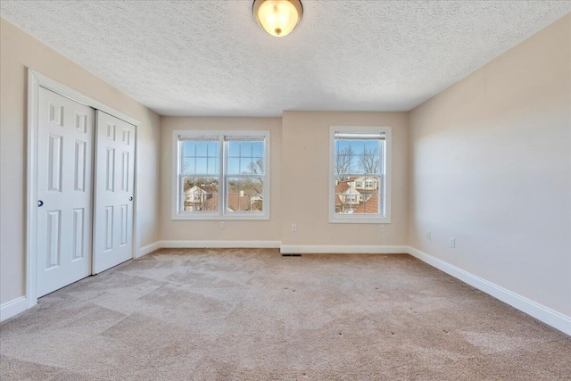 unfurnished bedroom featuring visible vents, a textured ceiling, a closet, carpet flooring, and baseboards