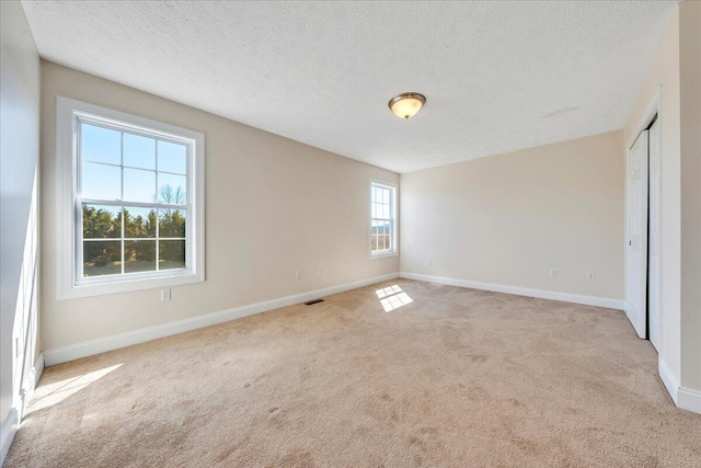 unfurnished bedroom with baseboards, light carpet, and a textured ceiling