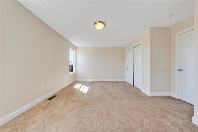 interior space with light colored carpet, baseboards, a closet, and a textured ceiling