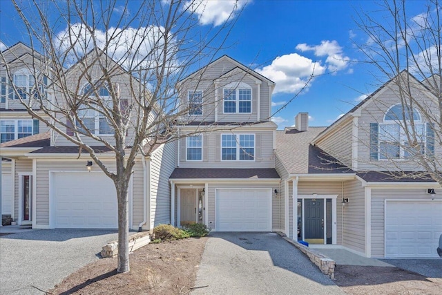 view of front of house featuring an attached garage, a chimney, driveway, and roof with shingles