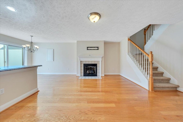 unfurnished living room with baseboards, light wood-style floors, a fireplace, and stairs