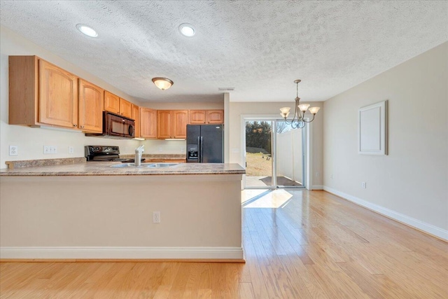 kitchen with light wood finished floors, baseboards, pendant lighting, a peninsula, and black appliances